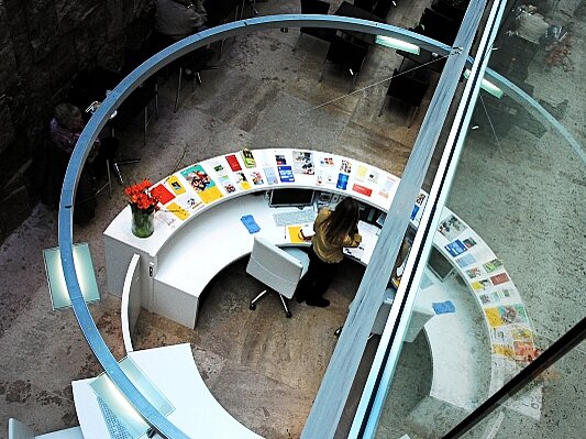 Ein Blick von oben auf das runde Informationszentrum mit seiner bunten Auslage